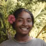 Yudris smiling, a pink hibiscus flower in her hair